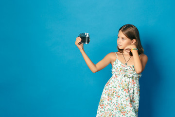 beautiful smiling child (girl) with white teeth holding a camera and making selfie