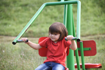 Fototapeta na wymiar Little boy workout exercise in park. Happy child exercise on outdoors gym