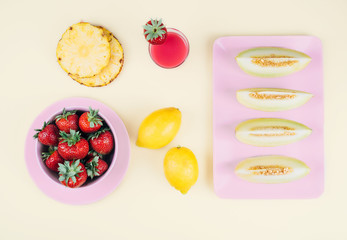 Fresh strawberries in bowl and melone on pastel yellow background.