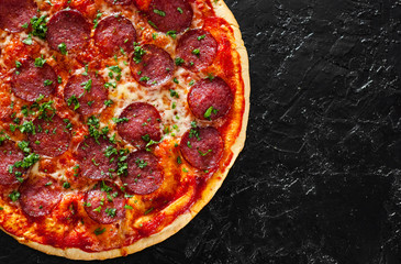 Pepperoni Pizza with Mozzarella cheese, salami, Tomatoes, pepper, Spices and Fresh Basil. Italian pizza on black background. with copy space. top view