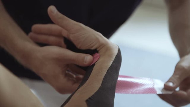View of unrecognizable therapist glues plaster on male hand and wrist