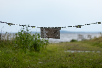 Vintage wooden sign blocking a road with a chain
