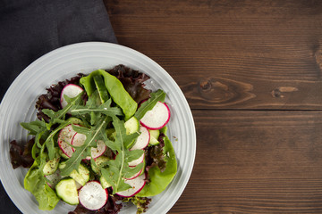 vegetarian salad in a plate on a wooden table, dark, top view