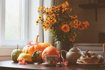 cozy autumn breakfast on table in country house. Hot tea, pumpkins, bagels and flowers.