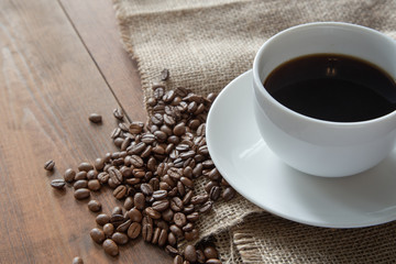 White coffee cup with coffee beans on wooden table. Top view