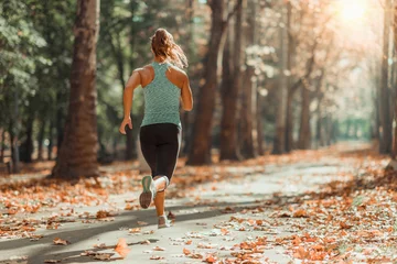 Fotobehang Vrouw joggen buiten in de herfst © Microgen