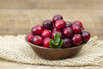 Cranberries in wooden bowl on wooden background.