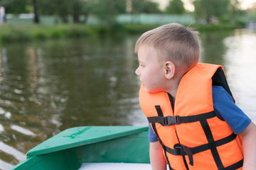 A little boy in a life jacket in a boat.
