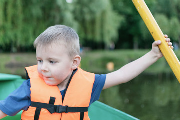 A little boy in a life jacket in a boat.