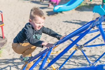 A little boy is climbing the structure. Children's outdoor activities.