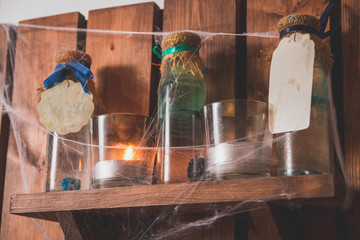 Common living room with sofa and fireplace decorated with Halloween toys and crafts such as lanterns, frames with ghosts, paper bats and withes, big ghost from fabric and broom.