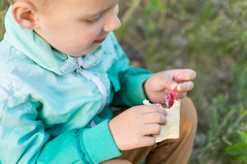 A little boy of 3-5 years eats on nature. Snack during a walk in the fresh air.