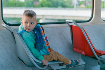 A little boy goes by himself on a tram. Travel of a child in public transport.