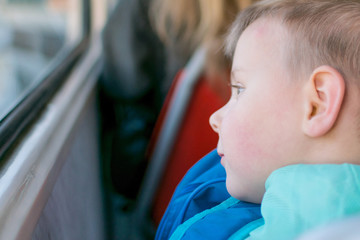 A little boy goes by himself on a tram. Travel of a child in public transport.