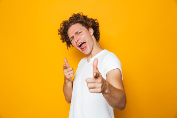 Portrait of a cheerful curly haired man pointing at camera
