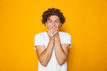 Fototapeta na wymiar Portrait of a shocked curly haired man covering mouth