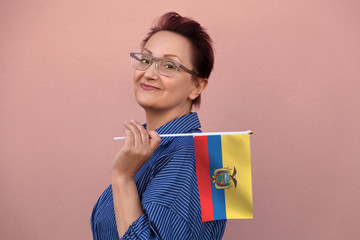 Ecuador flag. Woman holding Ecuadorian flag. Nice portrait of middle aged lady 40 50 years old with a national flag over pink wall background outdoor.