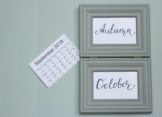 It`s a wooden green frame with the words Autumn and October. A full calendar of month of September 2018 is near. The whole composition is on a nice mint color wooden table. Plan begin of autumn.