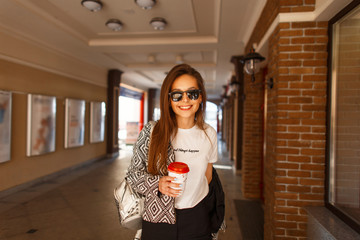 Fashionable happy woman with sunglasses in a fashion jacket and a white T-shirt walking in the city