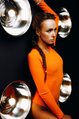 Girl on a beautiful background.Sexy girl in orange bodysuit.The girl with the braids