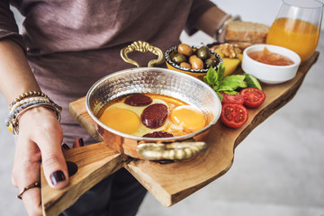 Woman carrying delicious traditional turkish breakfast on cutting board