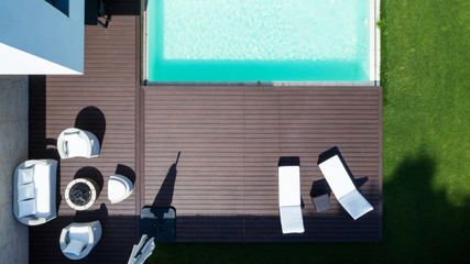 Detail of the swimming pool with deckchairs and lawn from above. Nobody inside