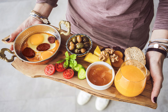 Woman carrying delicious traditional turkish breakfast on cutting board