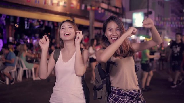 Traveler backpacker Asian women lesbian lgbt couple dancing together. Female drinking alcohol or beer with friends and having party at The Khao San Road in Bangkok, Thailand.