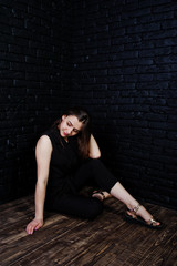 Fototapeta na wymiar Portrait of a beautiful brunette girl in black jumpsuit sitting and posing in the studio.
