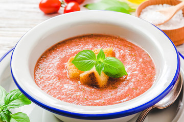 Healthy summer cold tomato soup, gazpacho with basil and garlic bread. Selective focus, space for text.