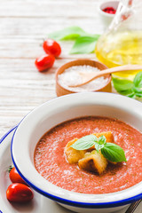 Healthy summer cold tomato soup, gazpacho with basil and garlic bread. Selective focus, space for text.