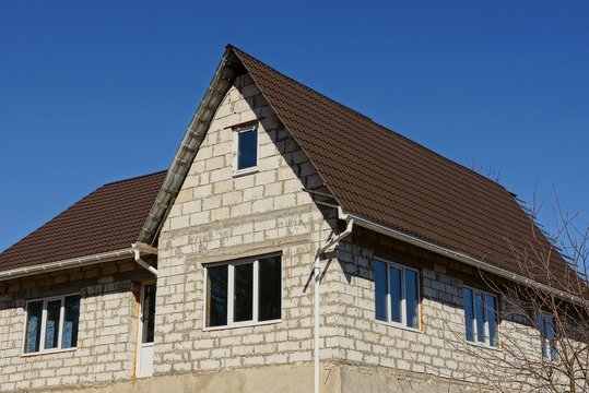 white brick house with a brown roof on the sky background