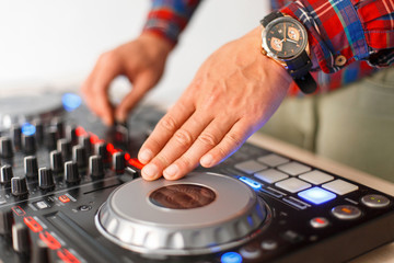 Man DJ plays on the mixing console close-up