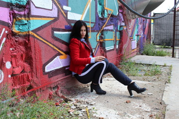 Young Woman leaning against Wall with Graffiti - Fashion Portrait
