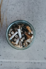 Smoked cigarette buns in a glass jar shot from the above.