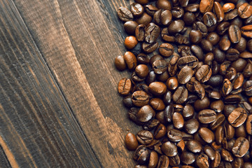 Grains of coffee close-up on a wooden brown background on the right side of the frame