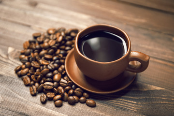 A cup of coffee and coffee beans on a dark wooden background