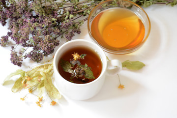 Cup of herbal tea, honey, herbs on a light background. Copy space