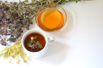 Cup of herbal tea, honey, herbs on a light background. Copy space