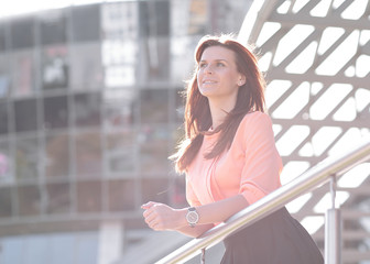 background image of a brooding business woman standing on the balcony of an office building