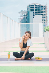 Image of happy young asian sports woman walking outdoors talking by mobile phone.