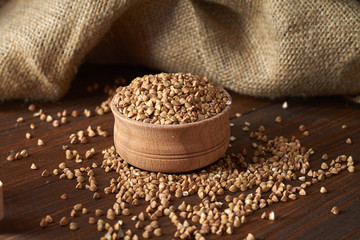 Brown buckwheat in a wooden bowl on a dark table