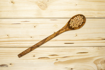 Lot of whole raw chickpeas kabuli variety with olivewood spoon flatlay on natural wood