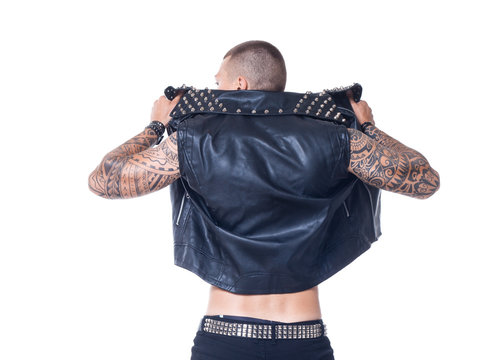 A Young Man Is Standing With His Back Dressed In A Black Leather Vest And Black Jeans With A Belt In Rhinestones On A White Background