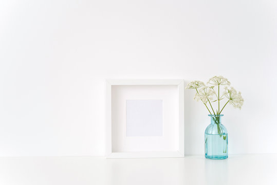 Minimal white square frame mock up with a Aegopodium in transparent blue vase. Mockup for quote, promotion, headline, design. Template for small businesses, lifestyle bloggers, social media