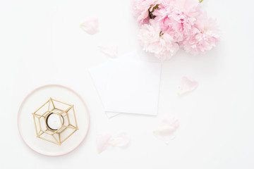 Feminine wedding or birthday flat lay composition with peonies floral bouquet and candle. Blank paper card, mockup, invitations. Flatlay, top view.