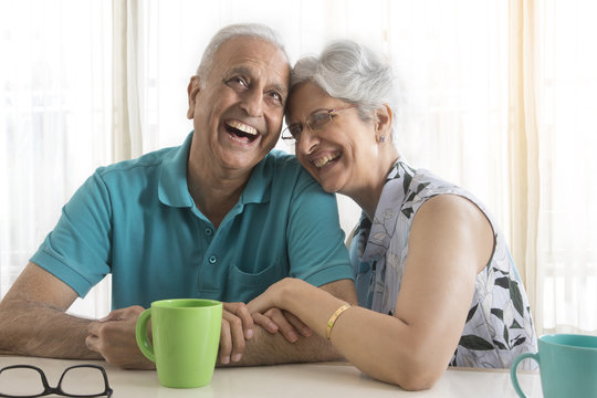 Senior couple laughing while drinking coffee at table
