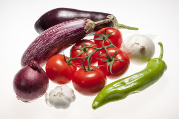 Fresh eggplants, tomatos, green pepper, onion and garlic over white background