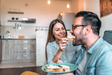 Couple having breakfast together. Girl feeding her boyfriend at home.