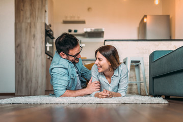 Laughing while lying on the floor. Couple having a good time at home.